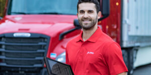 U.S. Xpress partner holding tablet while smiling at the camera.